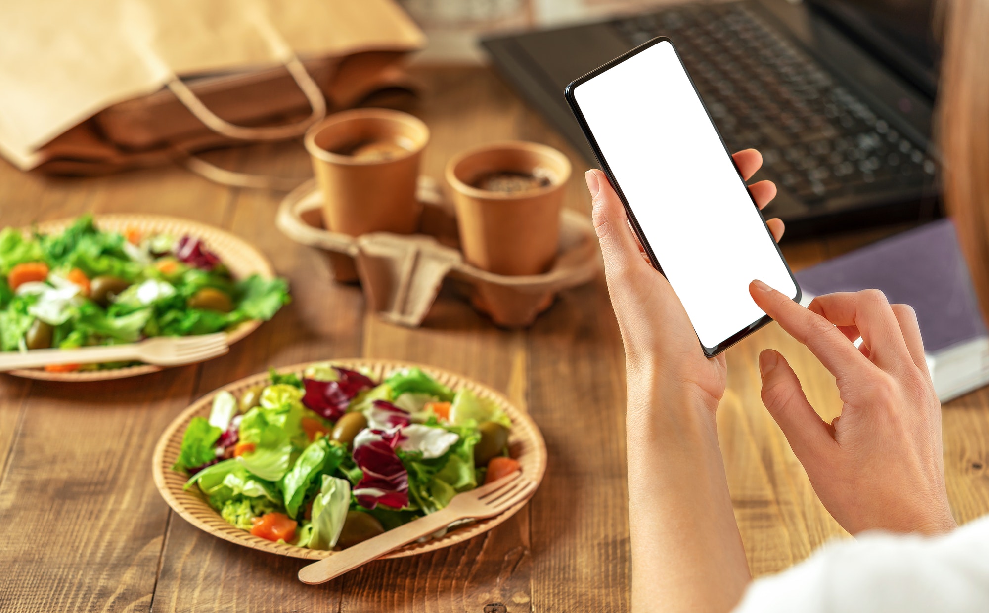 Female holding smartphone and and makes an order of healthy food through mobile app